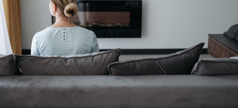 a woman sitting on a grey sofa and mentally preparing for the move