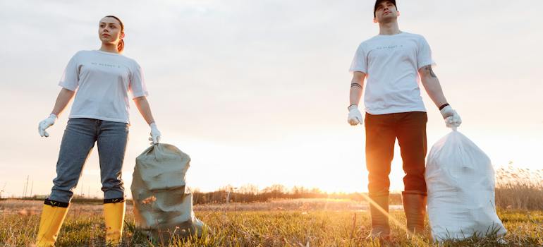 two people holding plastic bags full of waste they have just collected