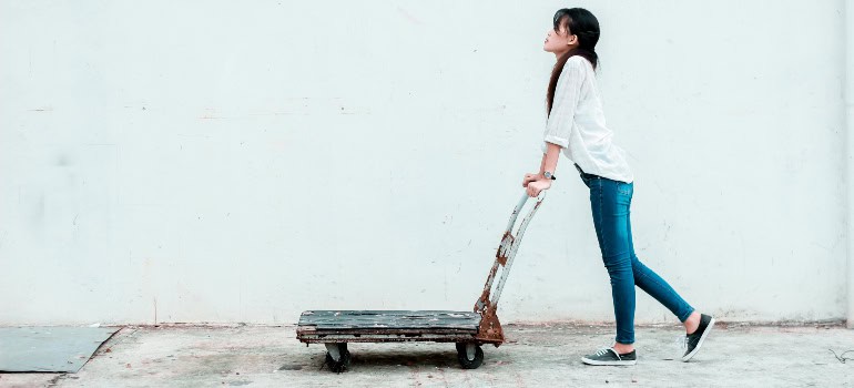 a woman pushing a dolly because she needs to move large household appliances