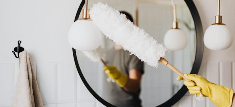 a person dusting a mirror as part of living alone for the first time in Falls Church VA