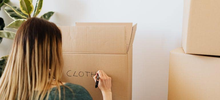 a woman writing something on a cardboard box