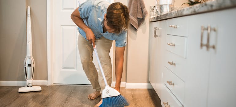 a man cleaning the kitchen floor because he intends to move large household appliances