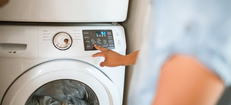 a man starting switching on a washing machine with children's clothes, which is a must when packing up baby items for your next child