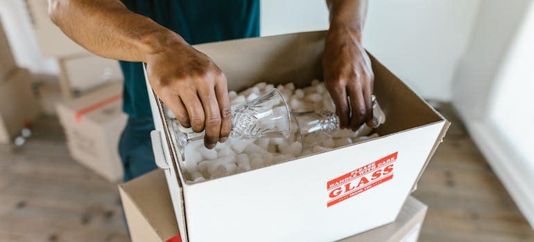  a professional mover packing some glasses in a box