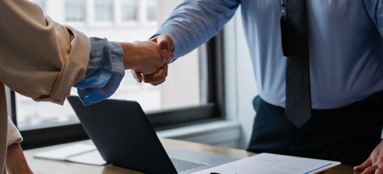 two people shaking hands after one of them managed in finding a reputable moving company