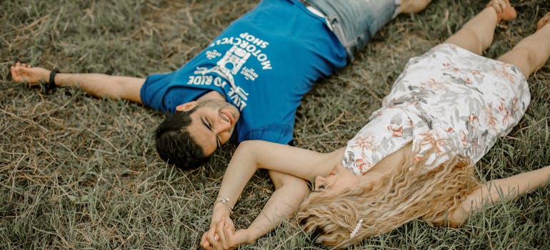 two people holding hands while lying on the grass