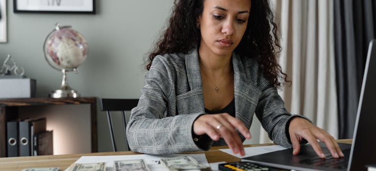 a woman calculating her budget by using a laptop and a mobile phone calculator