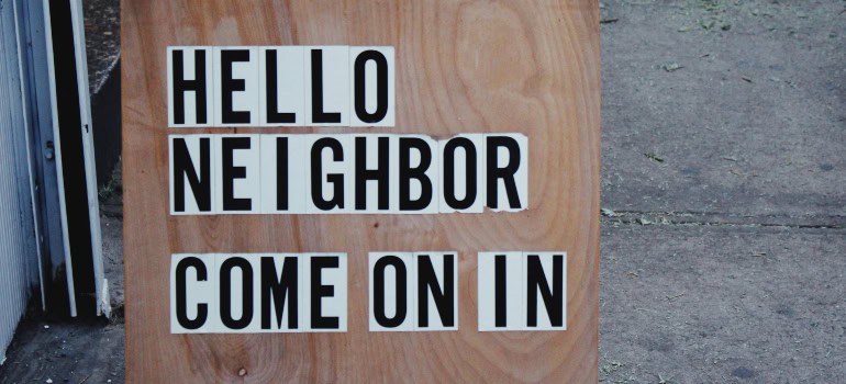 a wooden board with a sign on it that says "Hello neighbor, come on in"