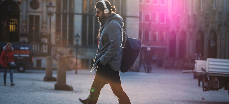 a man who is living alone in Northern VA is wearing headphones while walking down the street