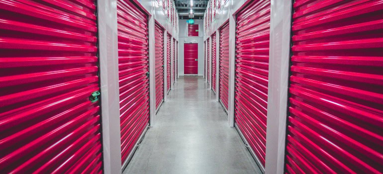 a hallway with many storage units with pink doors