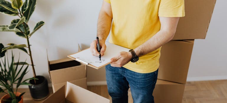 a man checking items off a list while standing next to some boxes