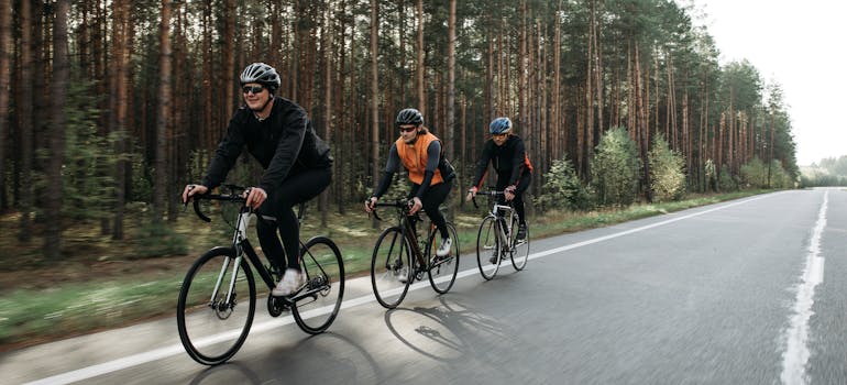 three people riding bikes along the side of the road