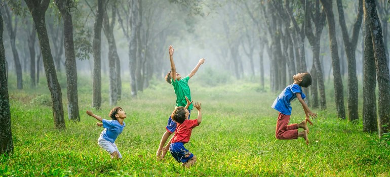 several boys playing with a ball in a forest 