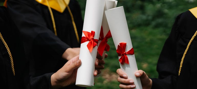 three students holding their diplomas