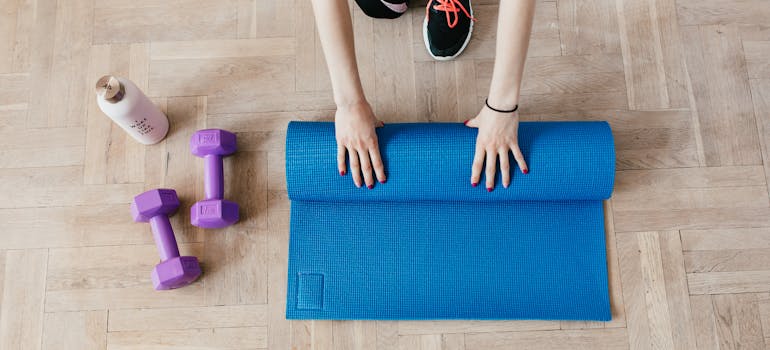 a woman rolling her yoga mat in her home