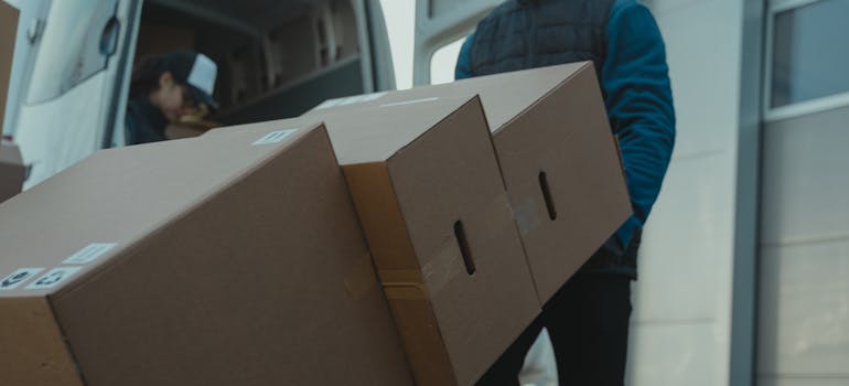 a man carrying three boxes at the same time by using a utility dolly.