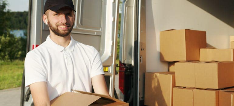 man standing next to a moving van with a smile on his face because he is happy people hire a local moving company 